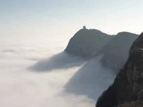 A mountain peak topped by a small pagoda rising out of a sea of cloud